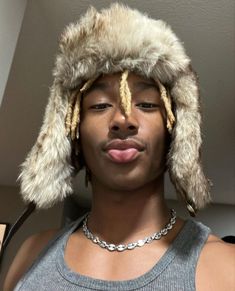 a young man wearing a fur hat and necklace