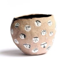 a ceramic vase with faces on it