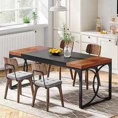 a dining room table with four chairs and a bowl of fruit on the table in front of it