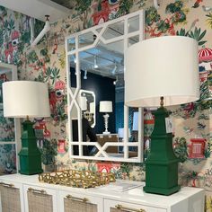 two lamps are sitting on top of a dresser in front of a wallpapered room