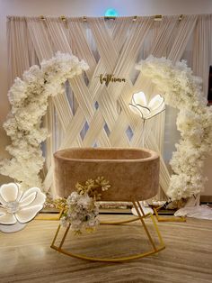 a flower arrangement in front of a window with white flowers on the side and gold stand