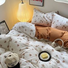 an unmade bed with white and brown comforter, headphones on the pillow