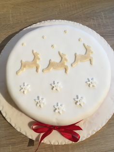 a white cake decorated with snowflakes and reindeers on the top is sitting on a plate