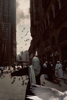 a group of people walking down a street next to tall buildings with birds flying overhead