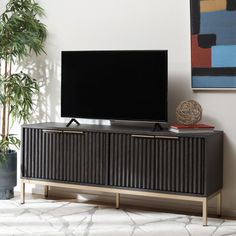 a flat screen tv sitting on top of a wooden entertainment center next to a potted plant