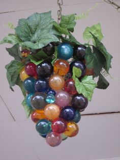 a bunch of glass balls hanging from a plant with green leaves on the top and bottom