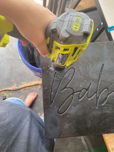 a person using a power drill on a sign that says booh in black and yellow