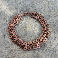 a close up of a metal bracelet on a stone surface with an oval design in the middle