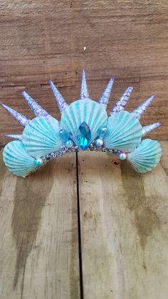 Handmade tourqoise with slight purple accents, real seashells, beautiful blue swarvoski jewel center and a splash of pearls with a glass bead accent makes this a unique tiara made on a 5 inch metal hair comb . Perfect to compliment that costume or for a party or any event.These are made with spiral shells that have a opening in the bottom some times beads get stuck inside while in the beading process so if you get it from shipping and beads are loosened up from being inside these openings...its Unique Tiara, Handmade Ocean-inspired Shell For Festivals, Shell Tiara, Sea Shell Crown Headpieces, Mermaid Shell Crown, Seashell Tiara, Mermaid Outfits, Ocean-inspired Beaded Shell, Mermaid Headpiece