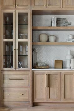 a wooden cabinet with glass doors and shelves filled with dishes, glasses and other items