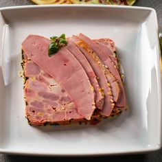 a white plate topped with slices of ham