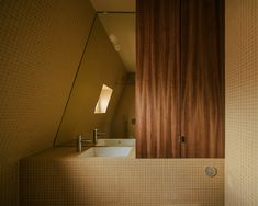 a bathroom sink sitting under a window next to a wooden cabinet in a room with tiled walls