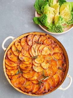 a dish with potatoes and lettuce next to a bowl full of cabbage leaves