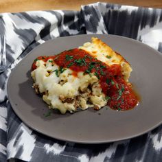 a white plate topped with lasagna covered in sauce