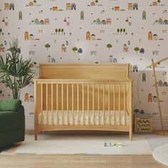 a baby's room with a crib, chair and wallpaper that has houses on it