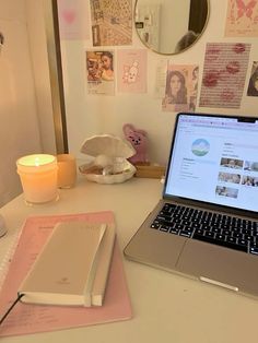 an open laptop computer sitting on top of a desk next to a candle and other items