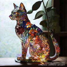 a stained glass cat sitting next to a potted plant