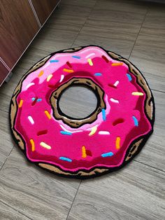 a pink donut rug with sprinkles sits on the floor next to an oven