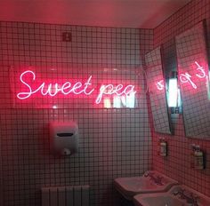 a bathroom with two sinks and a neon sign above the sink that says sweet peg