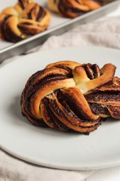 two pastries sitting on top of a white plate next to some silver trays