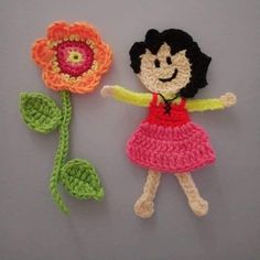 two crocheted dolls with one holding a flower