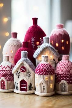 knitted houses with lights on them sitting on a table next to a christmas tree