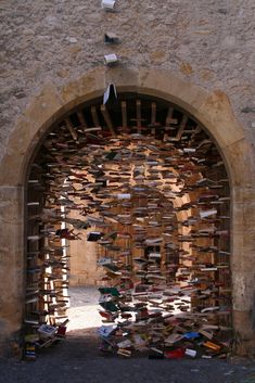 an arch with many books on it in the middle of a stone wall and door