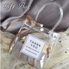 a thank you bag sitting on top of a white bed next to a gray blanket