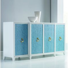 a blue and white cabinet with gold handles next to a bowl on top of it