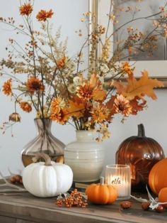 a table topped with vases filled with pumpkins and other fall decorating items