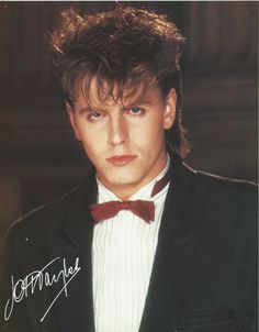 a man in a tuxedo and bow tie posing for a photo with his name on it