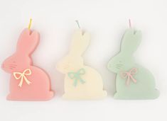 three candles shaped like bunnies with bows on the top one has a candle in the shape of a rabbit