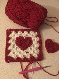 a crocheted heart sits next to a ball of yarn