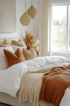 a bed with pillows and blankets on top of it in a bedroom next to a window