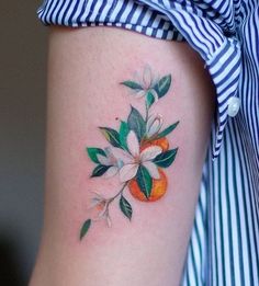 an orange and flower tattoo on the right side of the thigh, with green leaves