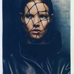 a woman wearing a black leather jacket and netted head covering her face with wire