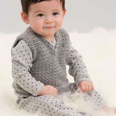 a little baby sitting on top of a fluffy white floor wearing a gray sweater and pants