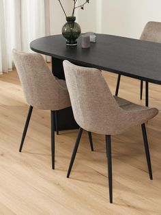 a dining table with four chairs and a vase on top of it in front of a window