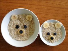 two white bowls filled with oatmeal topped with banana slices and blueberries