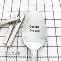 a spoon with the words custom design written on it next to some scissors and pliers