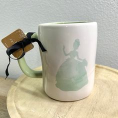 a coffee mug with a disney princess silhouette on it and a tag attached to the handle