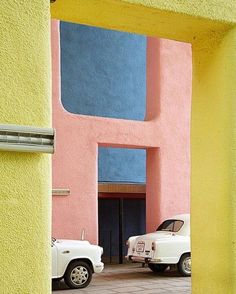 two white trucks parked in front of a pink and blue building