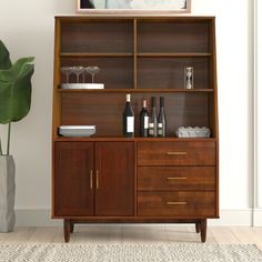 a wooden bookcase with wine bottles and glasses on it next to a potted plant