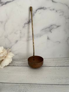 a white flower and a wooden bowl on a marble counter top with a gold spoon