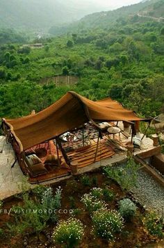 a tent set up in the middle of a lush green forest