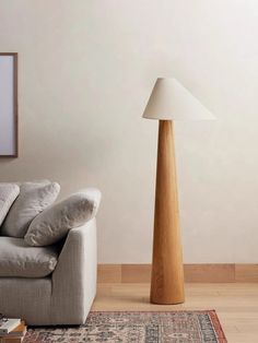 a living room with a white couch and wooden floor lamp next to it on top of a rug