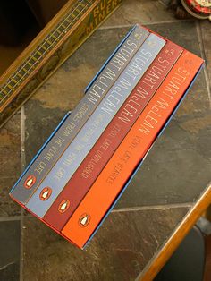 three books sitting on top of a wooden table