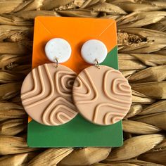 a pair of brown and white earrings sitting on top of a piece of paper next to some grass