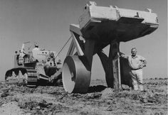 a man standing next to a large object in the desert