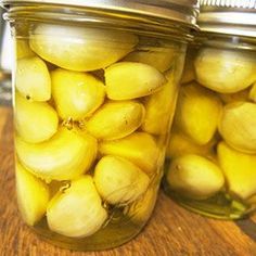 two jars filled with pickles sitting on top of a wooden table